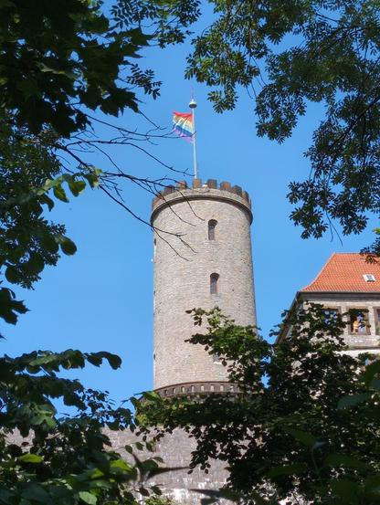 Die Regenbogenfahne gehisst auf dem Turm der Bielefelder Sparrenburg vor blauem Himmel