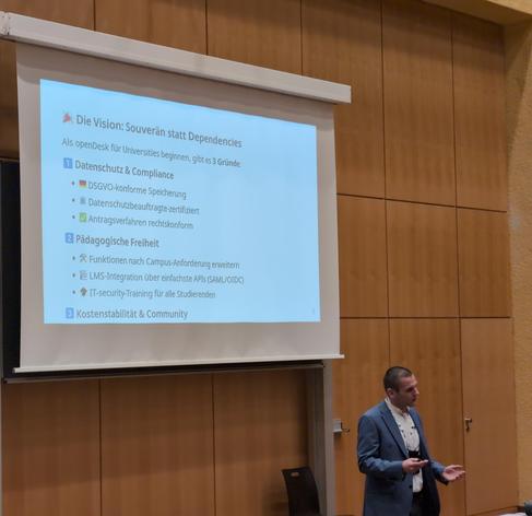 Dr. Tobias Weiß präsentiert bei den Chemnitzer Linuxtagen in einem Hörsaal der TU.

Überschrift auf der Folie:
"Die Vision: Souverän statt Dependencies"