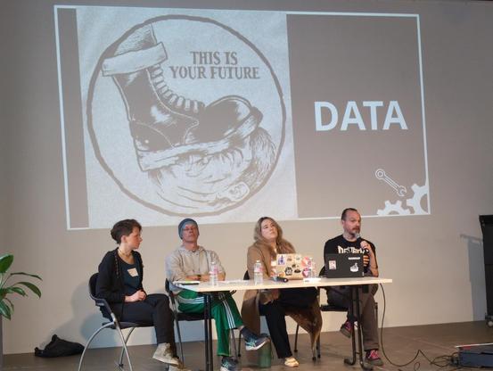 Jurgen und andere auf dem Podium bei den Cables of Resistance. Dahinter eine Folie von Tante:

Data – this is your future

mit einem Bild, das einen Stiefel zeigt, der einen Menschen zertritt