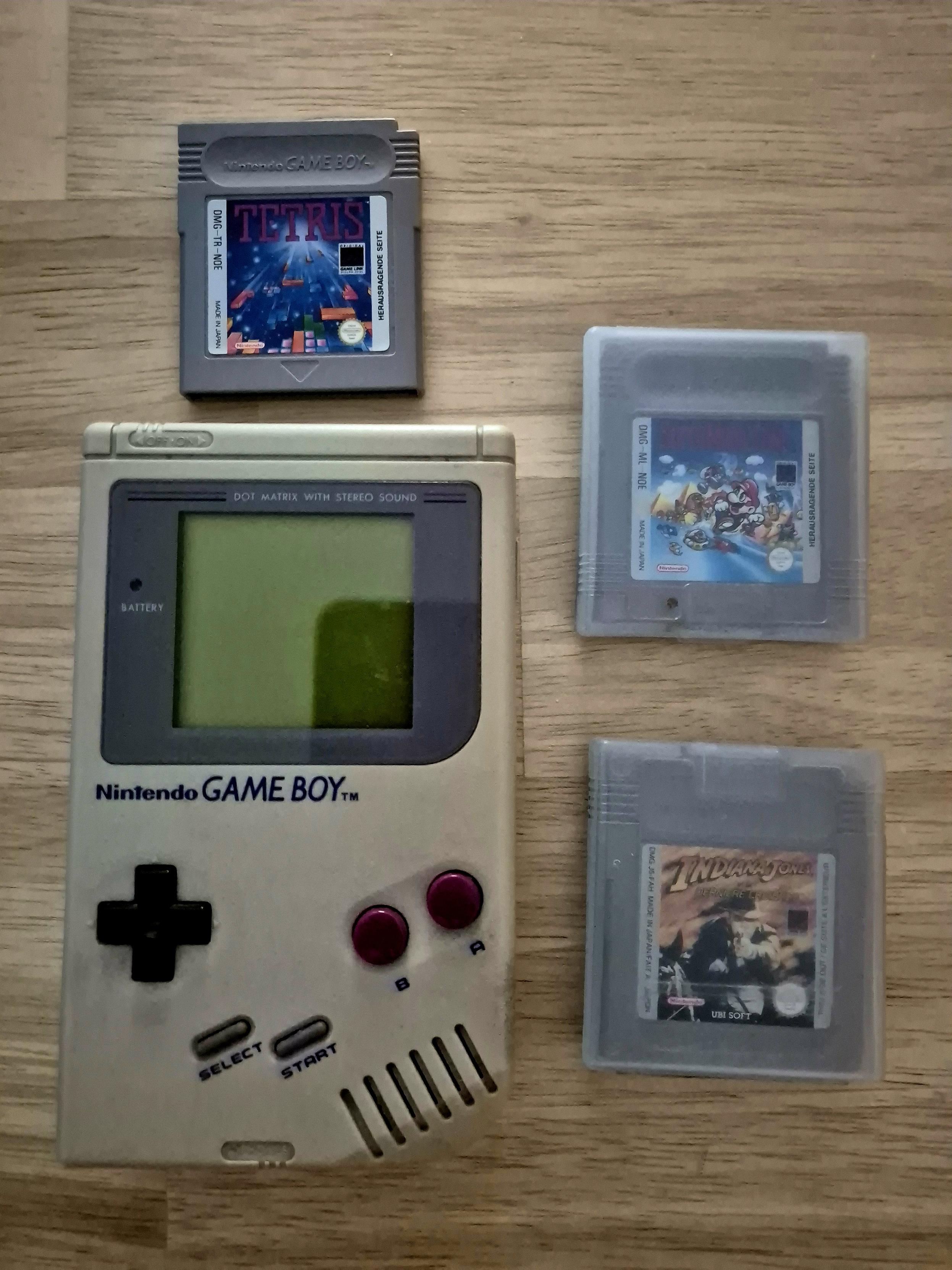 Auf einer Tischplatte liegt ein alter Game Boy und drei Spiele: Tetris, Super Mario Land und Indiana Jones.